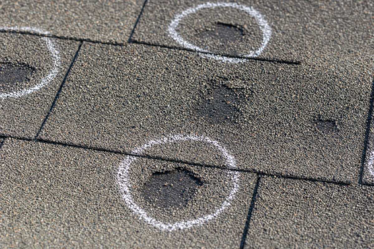 Hail damage on asphalt shingles in Carrollton, TX with impact bruises marked in chalk for the insurance adjuster